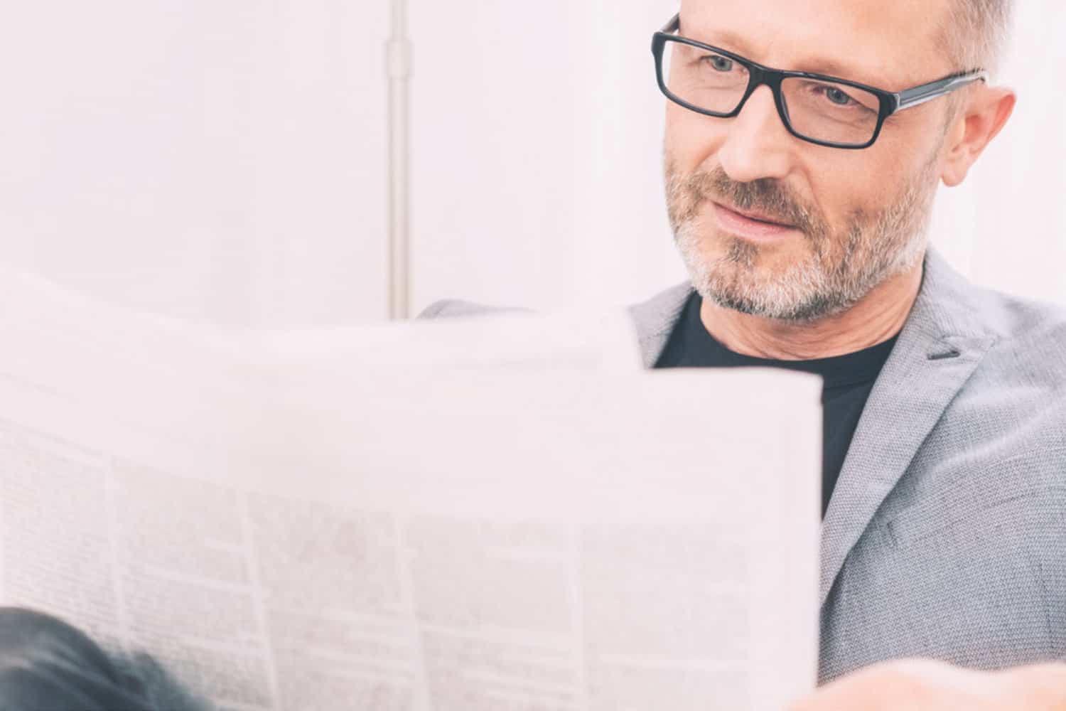 Retired man reading a newspaper on his couch